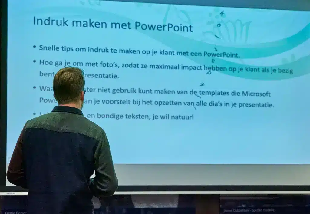 Aad Wagner staat voor een groot scherm met een PowerPoint sjabloon dat slecht is ontworpen.
